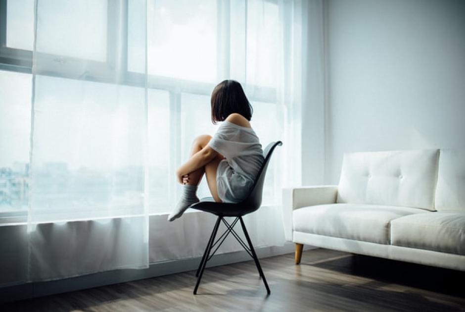 γυναίκα με κατάθλιψη κοιτάζει από το παράθυρο του σπιτιού της