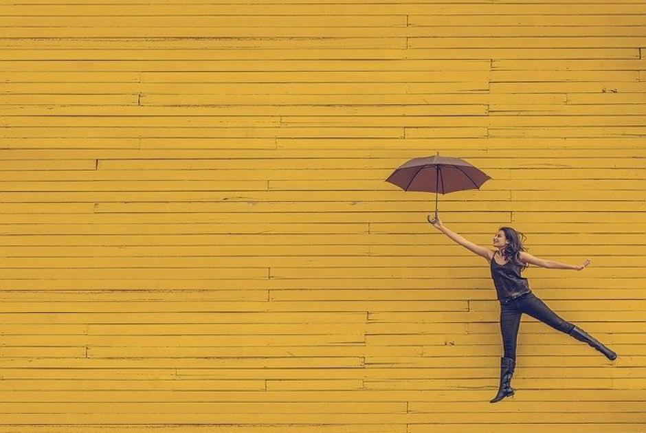 ευτυχία κοπέλα με ομπρέλα σε κίτρινο φόντο 