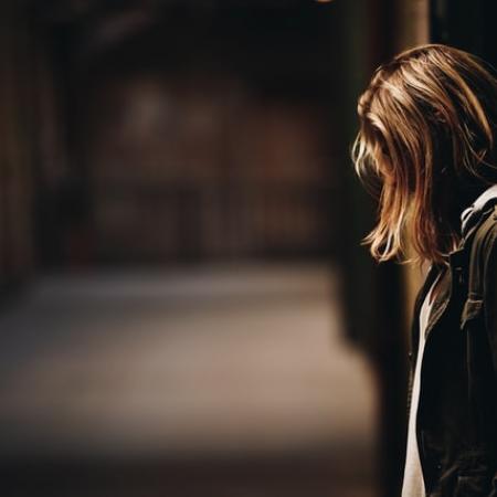 γυναίκα στεναχωρημένη κάθεται σε σκοτεινό σοκάκι