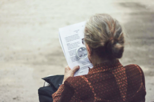 ηλικιωμένη γυναίκα γυρισμένη πλάτη που διαβάζει εφημερίδα